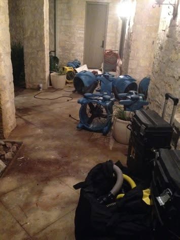 Row of air movers drying a covered patio slab after storm water intrusion near Largo, FL