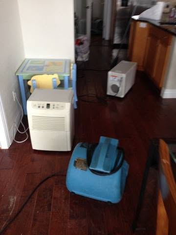 Dehumidifier and air mover drying a kitchen floor after an appliance leak in Largo, FL