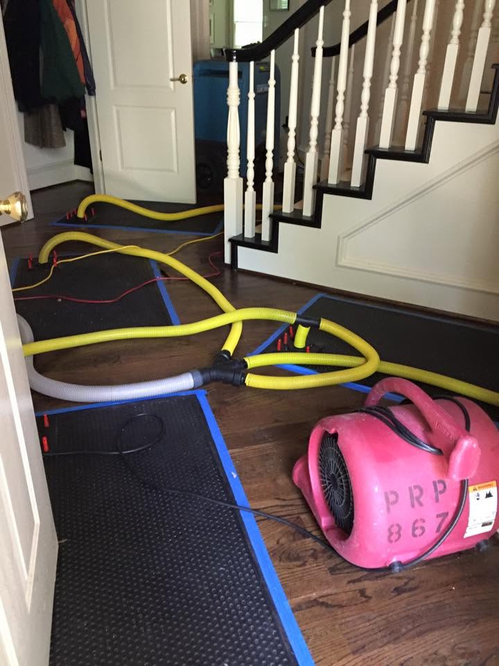 Air movers and hose lines drying a hardwood hallway during water damage restoration in a Largo, FL home